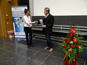 A photo shows how Andreas Fröba hands over the poster prize certificate to Frances D. Lenahan.