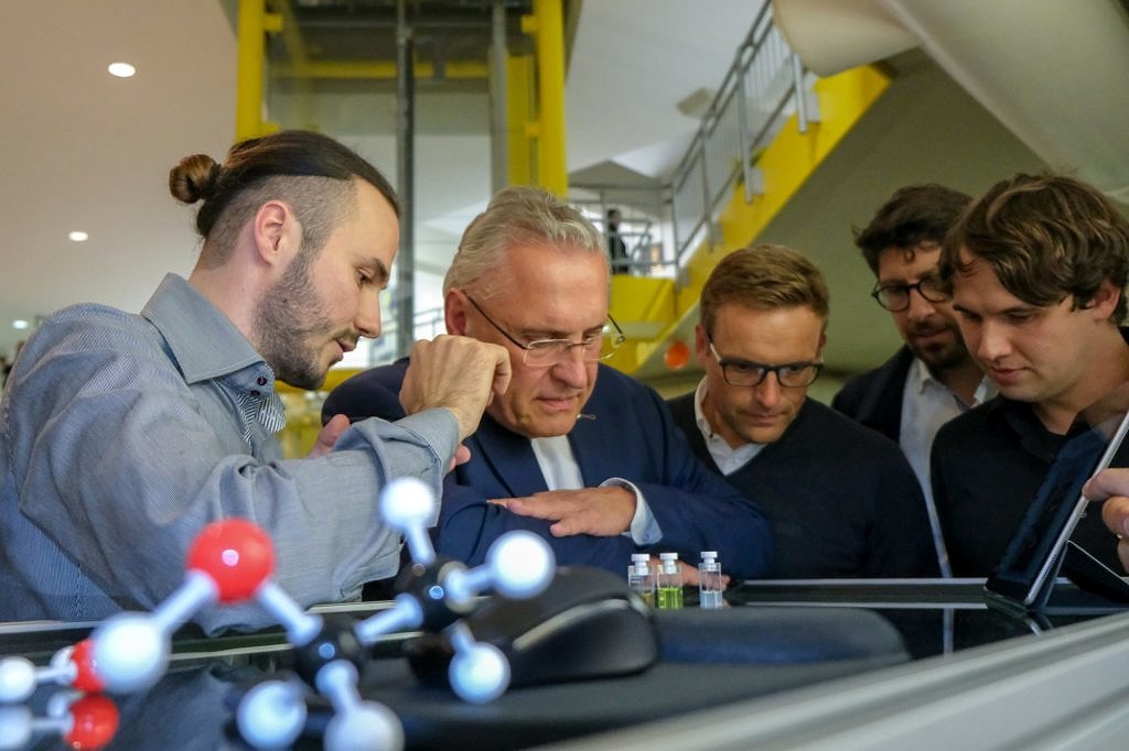 Photograph where Maximilian Piszko and Tobias Klein show the DLS experiment to Joachim Herrmann and other members of the VIP tour