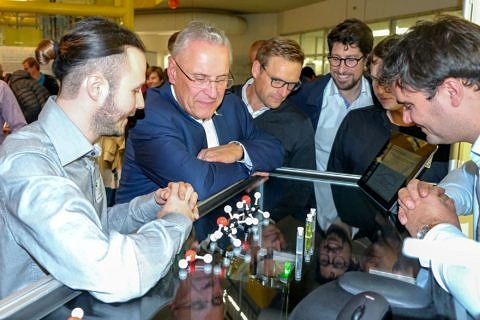 Maximilian Piszko, Cédric Giraudet and Tobias Klein show the DLS experiment to Joachim Herrmann and other members of the VIP tour (photo: Albrecht Börner)
