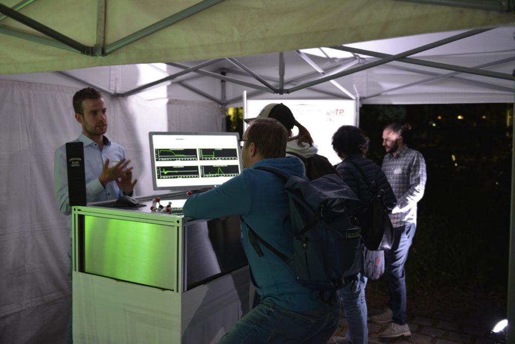 Photo showing Julius Jander and Maximilian Piszko explaining DLS measurements and the results to setup to some interested guests.